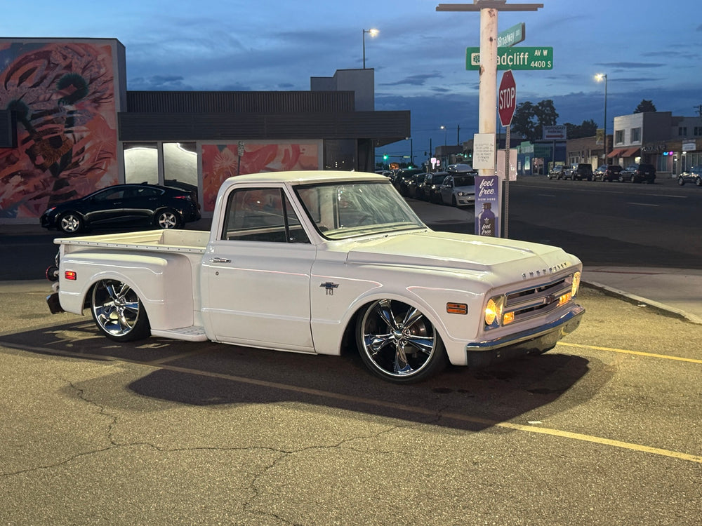 Evening front three-quarter photo of the white 1968 Chevrolet C10 Stepside with headlights illuminated.