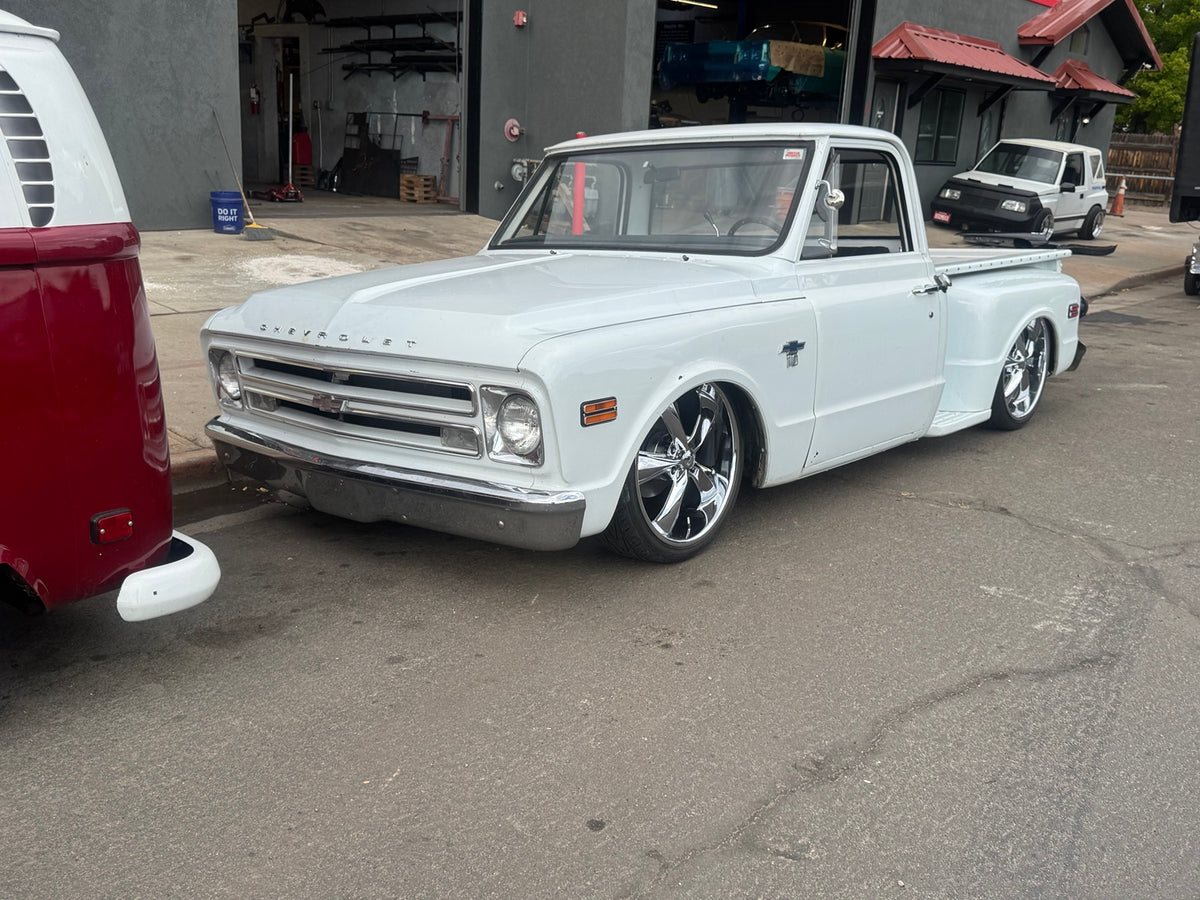 White 1968 Chevrolet C10 Stepside pickup in a front three-quarter view, showing its lowered stance and chrome wheels.