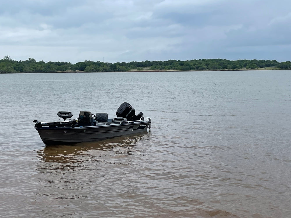 1990 Ranger Fisherman fishing boat pictured on the water with its Mercury outboard raised.