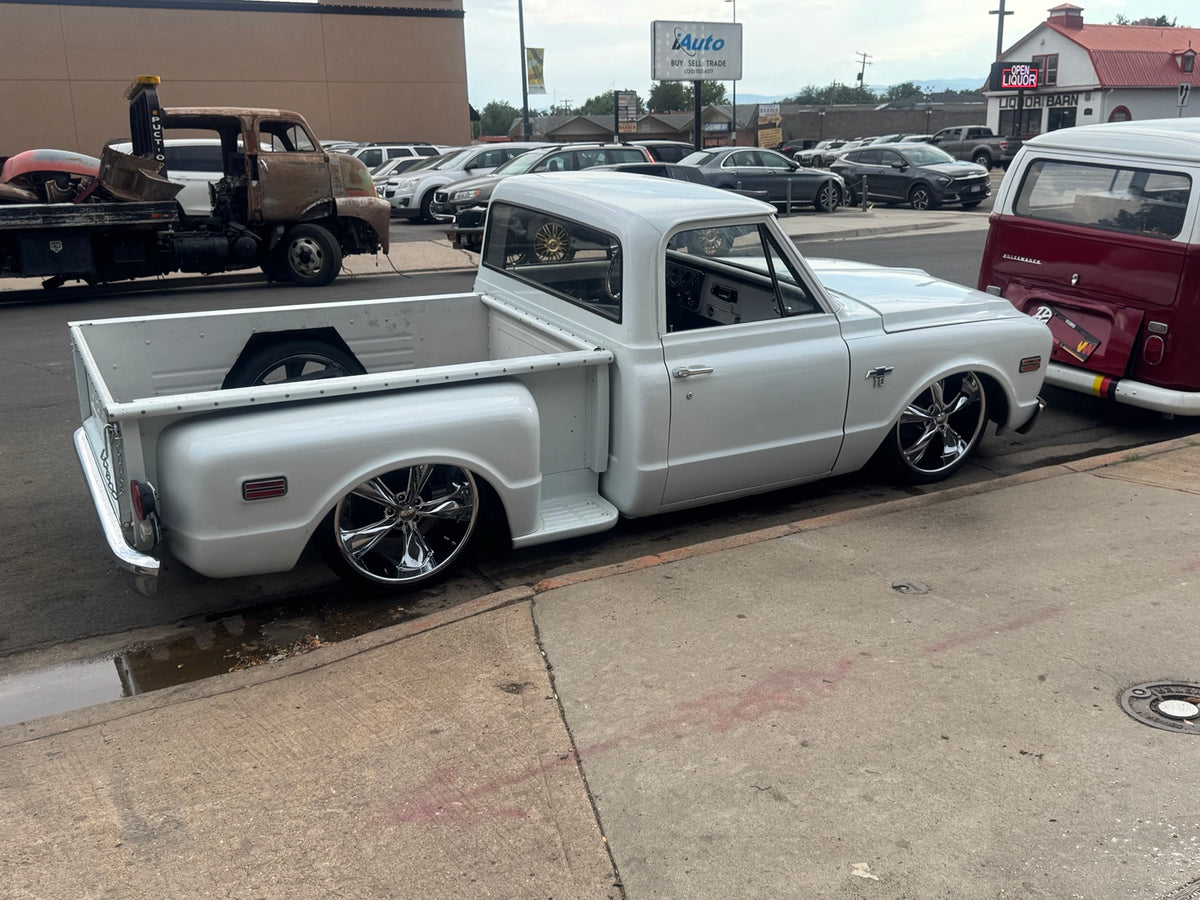Opposite rear three-quarter view of the white 1968 Chevrolet C10 Stepside, showing the bed, cab and chrome wheels.