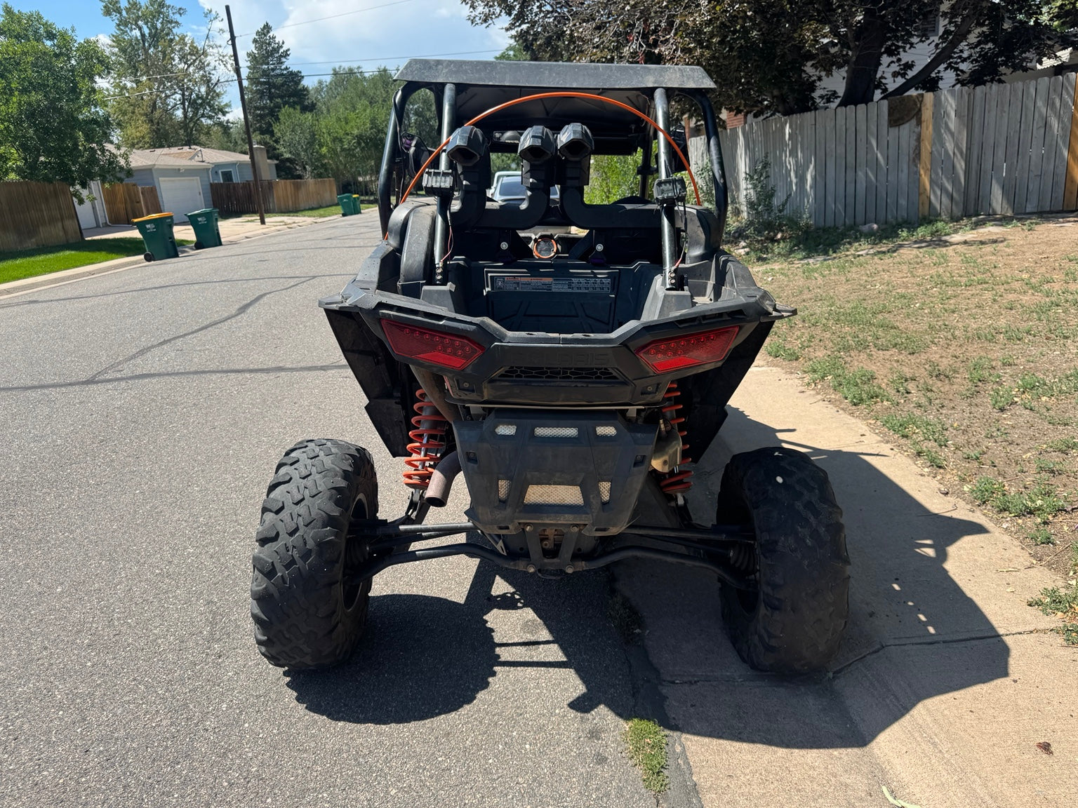 Rear view of the 2018 Polaris RZR XP 1000 High Lifter showing cargo area, raised intake tubes, exhaust and tires.